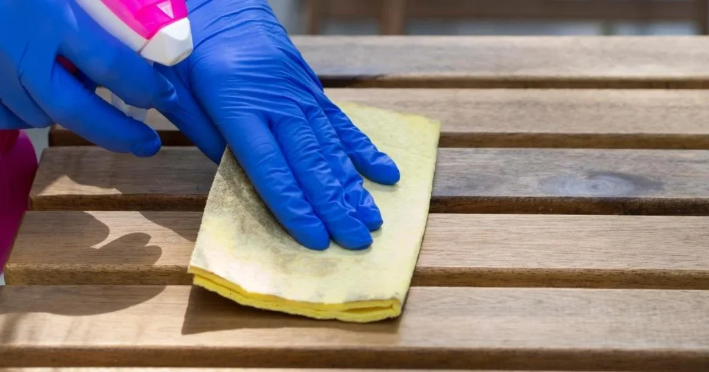 Hand met handschoen maakt een houten tafel schoon